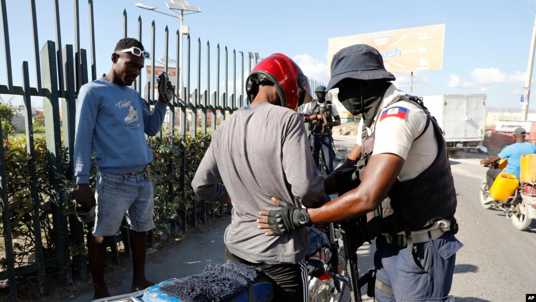 Seorang petugas polisi memeriksa seorang pengendara motor di titik pemeriksaan di Port-au-Prince, Haiti, pada 26 Januari 2024. (Foto: AP/Odelyn Joseph)