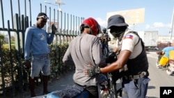 FILE - A police officer pats down a motorcyclist at a checkpoint in Port-au-Prince, Haiti, Jan. 26, 2024. A court in Kenya on Friday blocked the deployment of a U.N.-backed police force to help fight gangs in the troubled Caribbean country. 