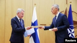 El ministro de Asuntos Exteriores finlandés, Pekka Haavisto, entrega los documentos de adhesión a la Alianza Atlántica al secretario general de la OTAN, Jens Stoltenberg, en Bruselas, el 4 de abril de 2023.