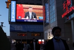 A giant screen shows news footage of Chinese President Xi Jinping attending a video summit on climate change from Beijing, China.