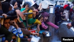 Anak-anak Palestina menunggu untuk menerima makanan selama bulan suci Ramadhan, saat konflik antara Israel dan Hamas berlanjut, di Rafah, di selatan Jalur Gaza 13 Maret 2024. (Foto: REUTERS/Mohammed Salem)