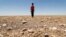 FILE - In this file photo a boy walks through a dried up agricultural field in the Saadiya area, north of Diyala in eastern Iraq on June 24, 2021