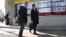 Men walk past an electronic stock indicator of a securities firm in Tokyo, Jan. 31, 2017.