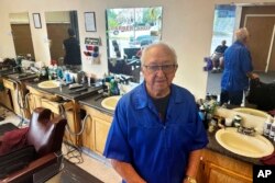 Eli Trujillo poses inside his barbershop in Cheyenne, Wyoming, July 18, 2024. Trujillo, 87, says he doesn’t work as many hours or cut hair as fast as he once did but isn’t one to judge whether U.S. President Joe Biden should continue to seek reelection.