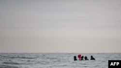 FILE - Migrants sit onboard a boat in the English Channel as they attempt to cross Aug. 27, 2020. 