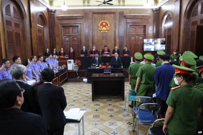 People stand before Vietnamese real estate tycoon Truong My Lan enters a courtroom in Ho Chi Minh City, Vietnam on Tuesday, March 5, 2024. (Phan Thanh Vu/VNA via AP)