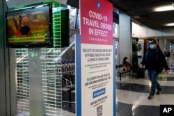 A traveler walks through Terminal 3 as a COVID-19 travel order sign is displayed at O'Hare International Airport in Chicago, Sunday, Nov. 29, 2020. Friday's total of new cases is the next-to-lowest daily number in the past 12 days, but Illinois…