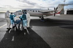Medical staff transport a patient affected with COVID-19 to be evacuated to another hospital, at Bron airport near Lyon, central France, Nov. 16, 2020.