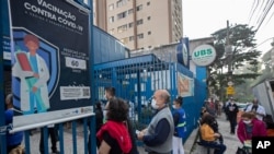 Personas hacen fila afuera de un centro médico comunitario para recibir una inyección de la vacuna Pfizer COVID-19 en Sao Paulo, Brasil, el jueves 6 de mayo de 2021.