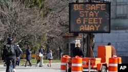 A large sign encourages people to practice social distancing by standing six feet apart as a precaution against the spread of COVID-19, outside the Grand Army Plaza entrance to Brooklyn's Prospect Park, in New York, Thursday, March 26, 2020. New…