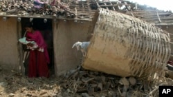 A woman carries her one-month-old child as she stands at the entrance of her house damaged in rainstorm in Bara district, 125 kilometers (75 miles) south of Kathmandu, Nepal, April 1, 2019. 