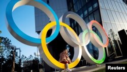 Seorang anak berpose di lambang cincin Olimpiade di depan Museum Olimpiade Jepang, di Tokyo, Jepang, 17 Februari 2020. (REUTERS/Athit Perawongmetha)