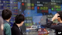 People look at an electronic stock indicator of a securities firm in Tokyo. Asian stocks were mostly higher Wednesday after Japan reported its first trade surplus in three years, April 22, 2015. 