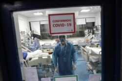 FILE - A health worker takes care of patients infected with the coronavirus disease inside an Intensive Care Unit of the Posta Central hospital in Santiago, Chile, June 9, 2020.