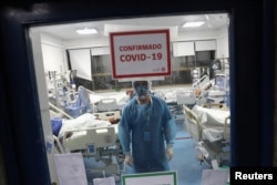 FILE - A health worker takes care of patients infected with the coronavirus disease inside an Intensive Care Unit of the Posta Central hospital in Santiago, Chile, June 9, 2020.