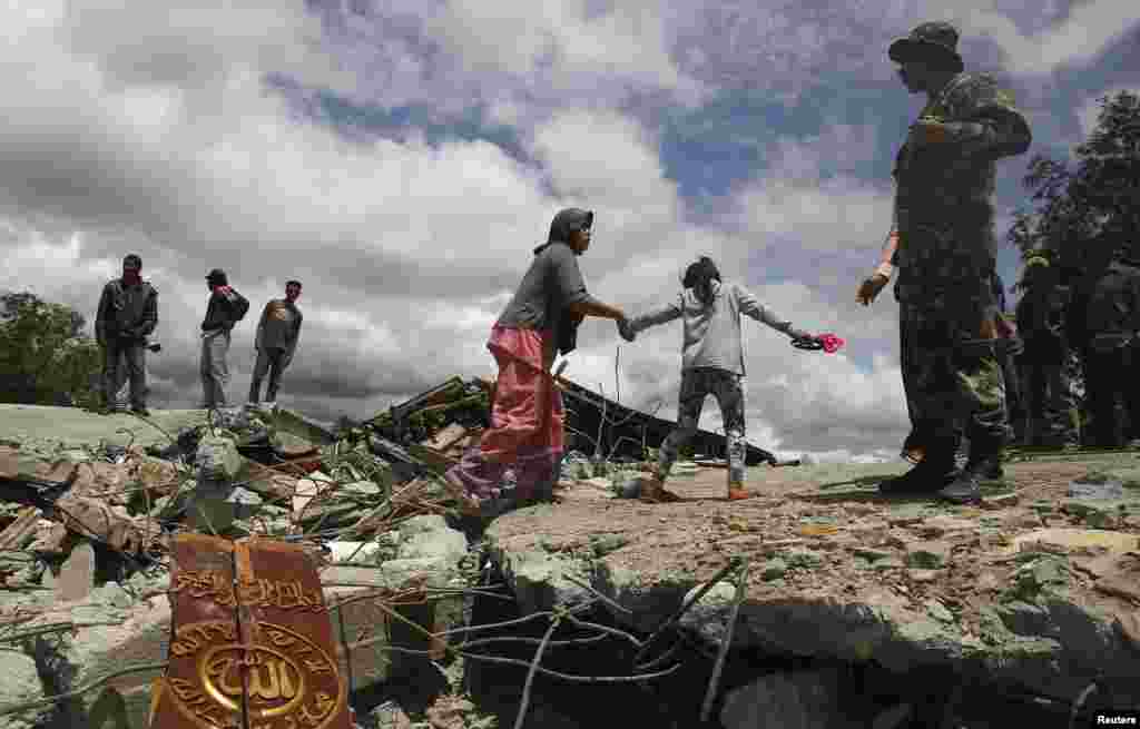 Warga berjalan di atas puing-puing masjid yang roboh di desa Blang Mancung akibat gempa berkekuatan 6,1 Skala Richter di Aceh tengah (3/7).