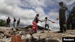 Warga berjalan di antara reruntuhan bangunan masjid yang hancur di desa Blang Mancung pasca gempa berkekuatan 6.2 SR mengguncang provinsi Aceh (3/7).