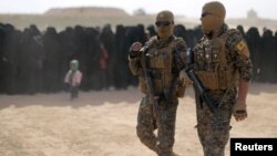 Fighters of Syrian Democratic Forces (SDF) walk together near Bagouz, Deir el-Zour province, Syria, March 5, 2019.