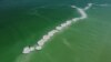 An aerial view shows beach-goers standing on salt formations in the Dead Sea near Ein Bokeq, Israel.