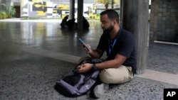 Student Gabriel Ortiz uses his cellphone at the Central University of Venezuela in Caracas, July 4, 2024. The man Ortiz was dating recently left crisis-ridden Venezuela, where the uncertainty is causing many young people to question whether it’s worth it to start a relationship.