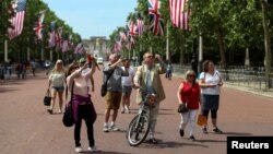 People photograph workers putting up U.S. flags along The Mall towards Buckingham Palace in central London ahead of U.S. President Donald Trump state visit to Britain, London, Britain, June 2, 2019.