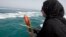 FILE - In a July 2, 2012, photo, Najmeh Arshad, an Iranian woman whose father was killed when a U.S. warship shot down an Iranian airliner July 3, 1988, scatters flowers into the Persian Gulf during a ceremony remembering the 290 passengers at the spot where the airliner was downed.