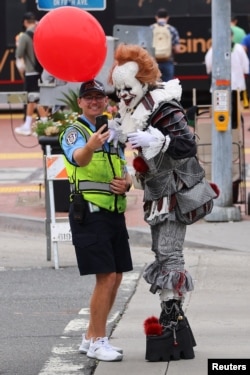 A San Diego traffic cop poses for a selfie with a person dressed as Pennywise from 'It', during the Comic-Con event in San Diego, California, USA, on July 21, 2023. [Foto: Reuters]