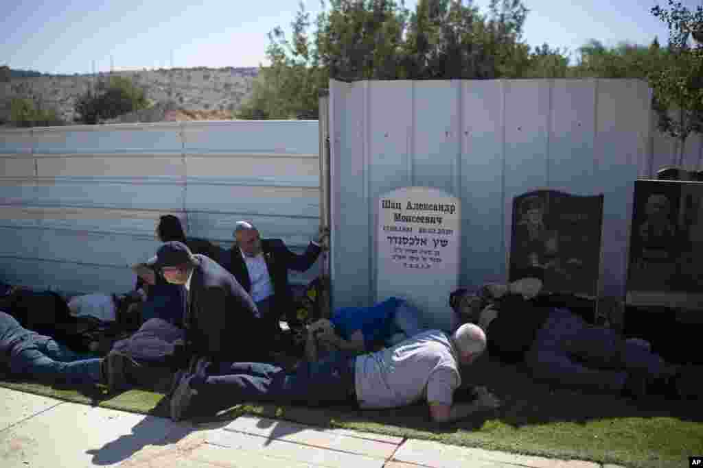 People take cover as a siren warns of incoming rockets during the funeral of Alexei Popov, who was killed during a rocket attack fired from Lebanon last weekend, at the Tel Regev cemetery in the outskirts of Haifa, northern Israel.