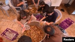 Relawan menyiapkan makanan untuk dibagikan kepada orang yang membutuhkan selama bulan suci Ramadhan, di Maan, Yordania 1 Mei 2021. (Foto: Reuters)