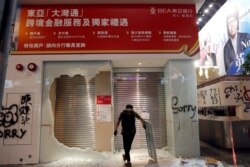 FILE - A man stands in front of the Bank of East Asia that was vandalized by anti-government protesters in Hong Kong, Oct. 20, 2019.