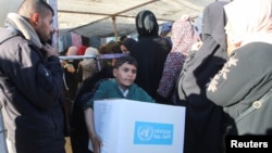 FILE - A Palestinian boy carries an aid box provided by UNRWA, following a ceasefire between Israel and Hamas, in Khan Younis in the southern Gaza Strip, Jan. 21, 2025.