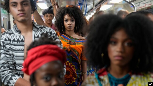 FILE - Models wear outfits designed by students from Afro-Brazilian communities at a subway station as part of Black Consciousness Awareness Month, in Sao Paulo, Brazil, November 19, 2021.