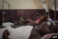FILE - A mother watches her HIV-positive child in the intensive care unit of the Bangui pediatric complex, while in the foreground, an HIV-positive child sleeps, in Central African Republic, Dec. 4, 2018.