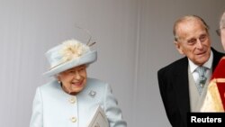 Ratu Inggris Elizabeth II dan Pangeran Philip menunggu kedatangan dengan kereta terbuka Putri Eugenie dari York dan Jack Brooksbank setelah pernikahan mereka di Kapel St George, Kastil Windsor, dekat London, Inggris, 12 Oktober 2018. (Foto: Reuters)