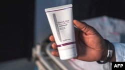 FILE - Aranmolate Ayobami, plastic surgeon at Grandville Medical and Laser clinic in Lagos, holds a tube of Skinlite a skin lightening product used at his clinic, on July 17, 2018, in Lagos, Nigeria.