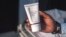 FILE - Aranmolate Ayobami, plastic surgeon at Grandville Medical and Laser clinic in Lagos, holds a tube of Skinlite a skin lightening product used at his clinic, on July 17, 2018, in Lagos, Nigeria.