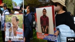 Para pengunjuk rasa memegang plakat pemimpin serikat pekerja Rong Chhun dan seorang pemuda yang ditangkap karena mengkritik pemerintah, 22 Oktober 2021. (Foto: VOA)