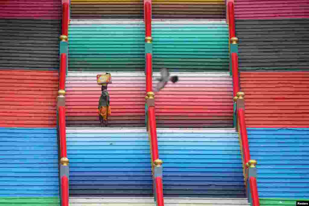 A man carries a box while climbing the steps to the Batu Caves in Kuala Lumpur, Malaysia.