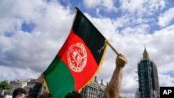A demonstrator walks holding an Afghanistan flag, during a protest at Parliament Square in London, Wednesday, Aug. 18, 2021. British Prime Minister Boris Johnson is set to update lawmakers Wednesday about the evacuation of British nationals and…