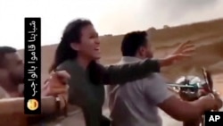 In this image from a video obtained by the AP, Noa Argamani reacts as she and her partner Avinatan Or, not pictured, are seized during a music festival in Israel on Saturday, Oct. 7, 2023. The writing in Arabic at left in the video reads, "Our guys have done their duty."