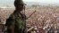 A soldier from the M23 rebel group looks on as thousands of Congolese people listen during an M23 rally, in Goma, eastern Congo, Nov. 21, 2012
