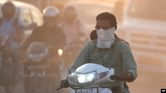 FILE -A man cover his face to protect from the dust in Ahmedabad, India, Wednesday, Feb. 5, 2025. (AP Photo/Ajit Solanki)