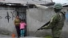 Un saldado captado en uno de los vecindarios en las afueras de Quito, Ecuador como parte de los despliegues de seguridad ordenados por el Gobierno para hacer frente a la ola de violencia. Una niña y su madre observan desde una humilde vivienda.