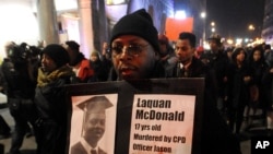 FILE - A protester holds a sign as people rally in memory of 17-year-old Laquan McDonald, who was shot 16 times by police officer Jason Van Dyke in Chicago, Nov. 24, 2015.