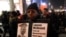 FILE - A protester holds a sign as people rally in memory of 17-year-old Laquan McDonald, who was shot 16 times by police officer Jason Van Dyke in Chicago, Nov. 24, 2015.