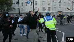 A police officer separates groups as bottles (R) are thrown, close to the 'National March For Palestine' in central London on November 11, 2023, as counter-protest groups are monitored by police close to the route of the main march.