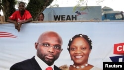 Un partisan de l'ancien footballeur et candidat à la présidence du Congrès pour le changement démocratique (CDC) George Weah se tient derrière une bannière de la campagne présidentielle à Monrovia, Libéria, le 6 octobre 2017.