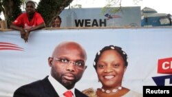 Un partisan de George Weah derrière une bannière de la campagne présidentielle à Monrovia, au Libéria, le 6 octobre 2017.