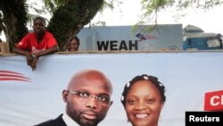 Un partisan de l'ancien footballeur et candidat à la présidence du Congrès pour le changement démocratique (CDC) George Weah se tient derrière une bannière de la campagne présidentielle à Monrovia, Libéria, le 6 octobre 2017.