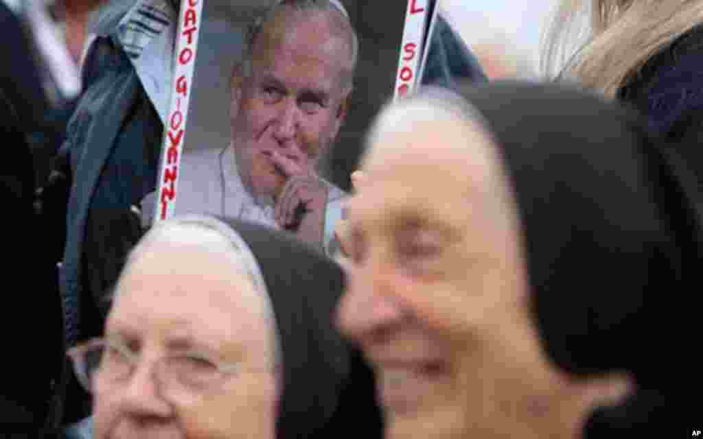 A picture of late Pope John Paul II, is framed by two nuns prior to the start of the Easter mass celebrated by Pope Benedict XVI in St. Peter's square, at the Vatican, April 24, 2011(AP)